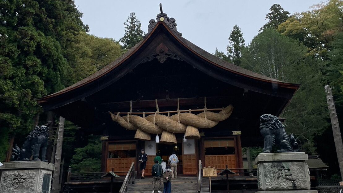 二体の狛犬の中央に大きなしめ縄が飾られた神楽殿が建っている