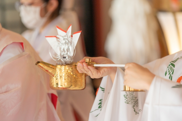 神前式の流れで巫女さんがお神酒を注いでいる