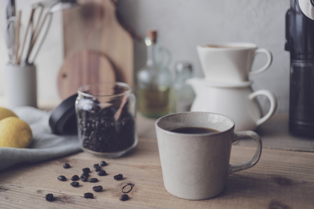 コーヒーの道具が並んでいる横にマグカップに入ったブラックコーヒーが置かれている